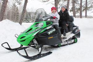 Two children on a green snowmobile
