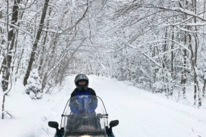 A rider on a snow covered trailed surrounded by snow capped trees